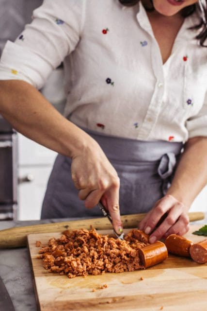 Smashing sausage into crumbles with a fork.