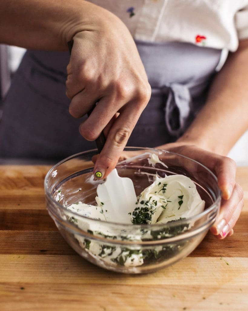 Stirring chopped parsley into cream cheese.