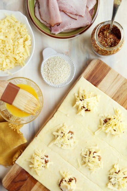 Cheese sprinkled over mustard on unbaked puff pastry