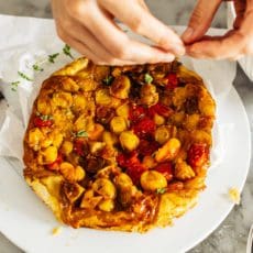 Tearing fresh herbs across baked tomato pie.