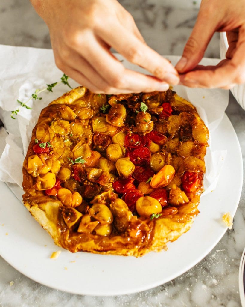 Tearing fresh herbs across baked tomato pie.