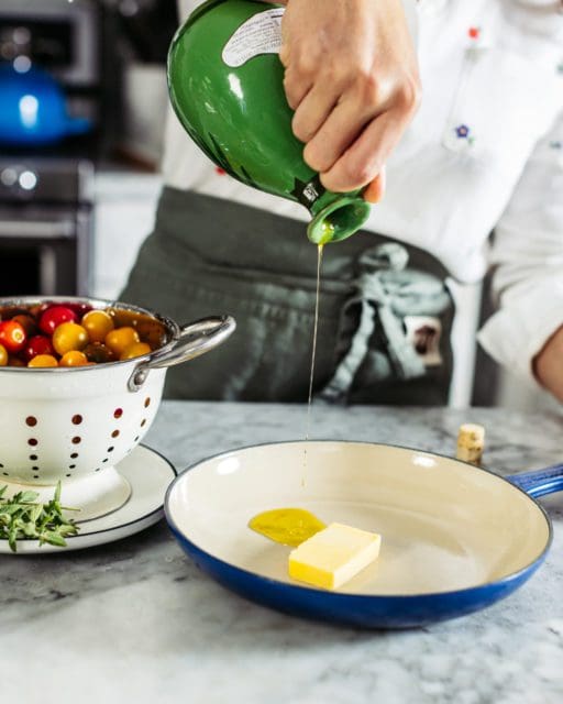 Pouring olive oil in a cast iron skillet with butter