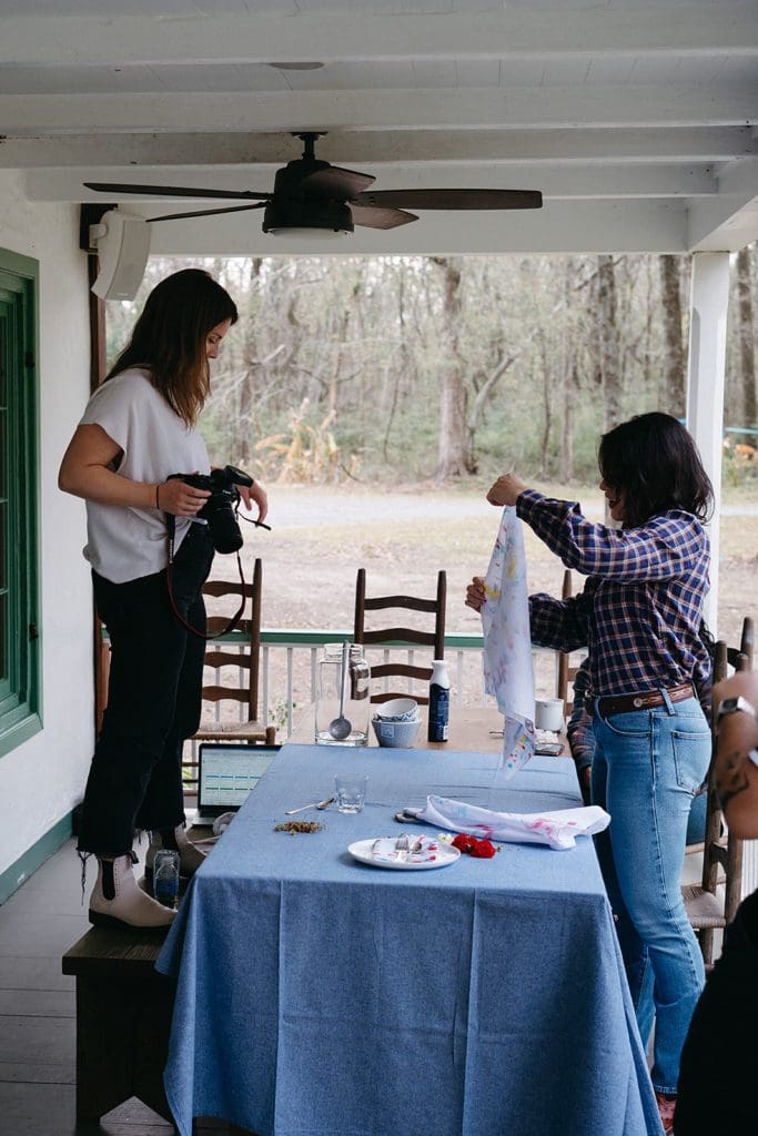Two people arranging dyed bandana on a set table.