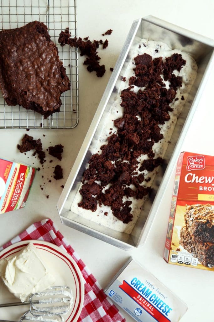 Ice cream in a loaf pan with brownies crumbled on top.