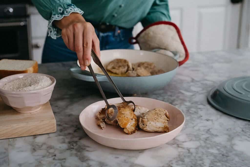 Cooked chicken thighs into bowl.