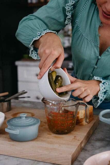 Pouring pickle juice from jar to measuring cup.