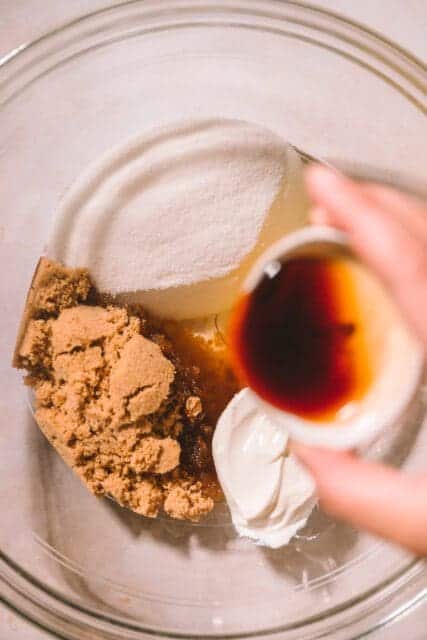 pouring vanilla into bowl with sugars and oil.