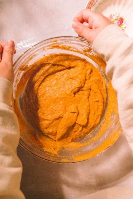 covering pumpkin muffin recipe with plastic wrap.