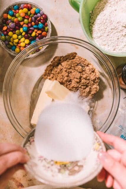 Pouring sugar into bowl with butter and brown sugar.