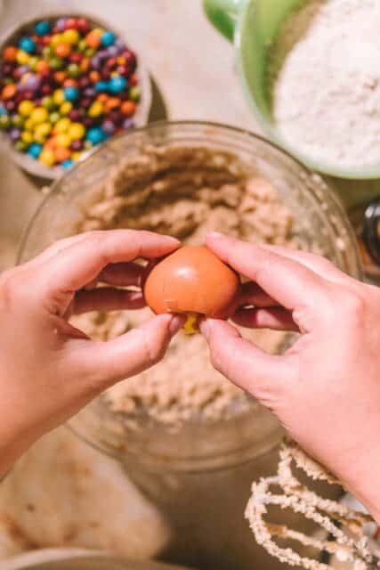 Cracking egg into creamed butter and sugar