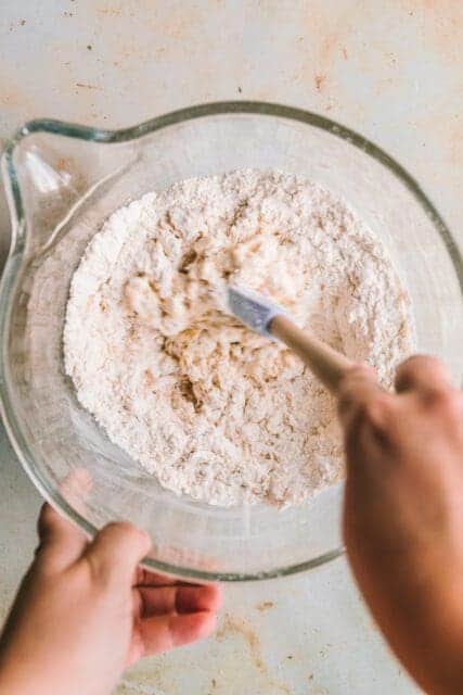 Stirring pull apart garlic bread dough with a rubber spatula.