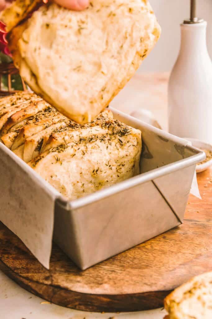 Pulling a piece of bread out of the pan.