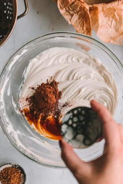 Adding chocolate powder, vanilla, and salt to cheesecake batter