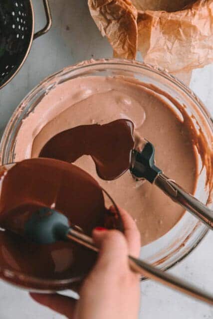 Pouring melted butter into cheesecake batter.