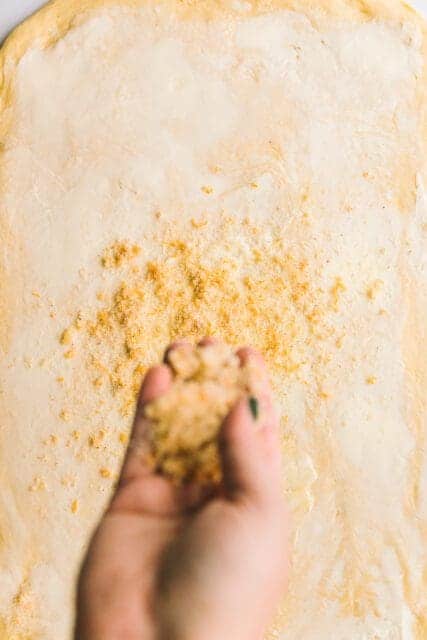 Sprinkling orange sugar on buttered dough.