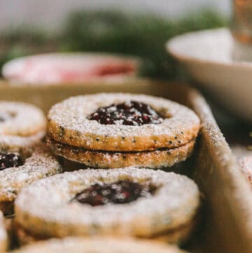 Raspberry linzer cookie recipe stacked on baking sheet.