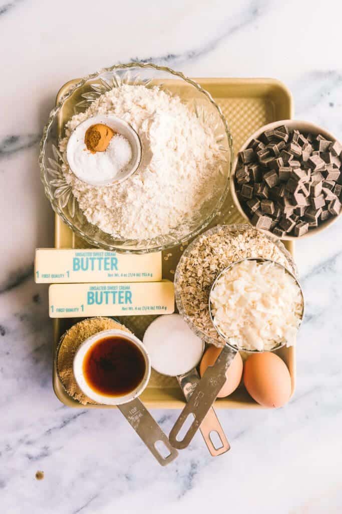 butter, flour, chocolate, vanilla, and eggs on a baking sheet for cowboy cookie recipe.