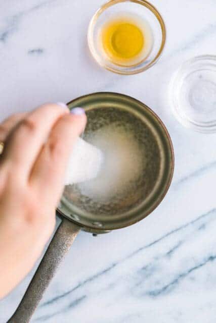pouring sugar into a pot to melt for simple syrup for bostsock