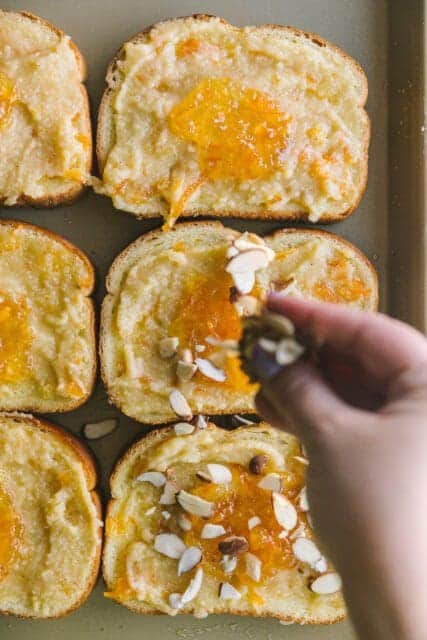 sprinkling ingredients on thick sliced bread covered in orange frangipane