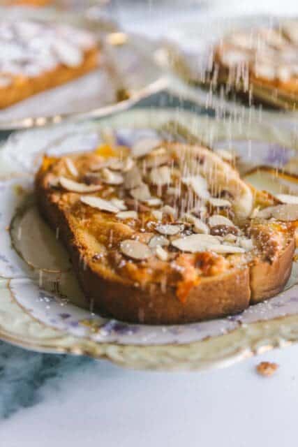 action shot of powdered sugar being sprinkled on Mardi Gras bostock toast