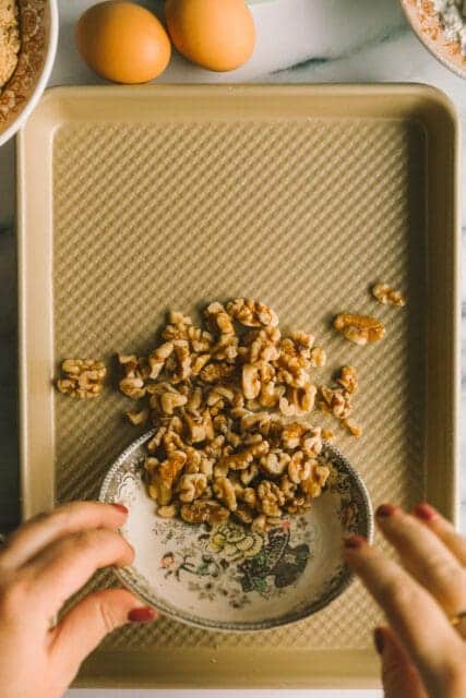 pouring nuts on a baking sheet to toast