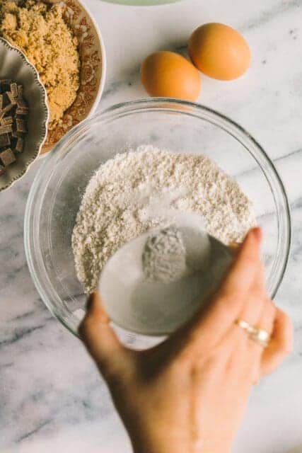 pouring salt into flour to whisk together for blondie recipe