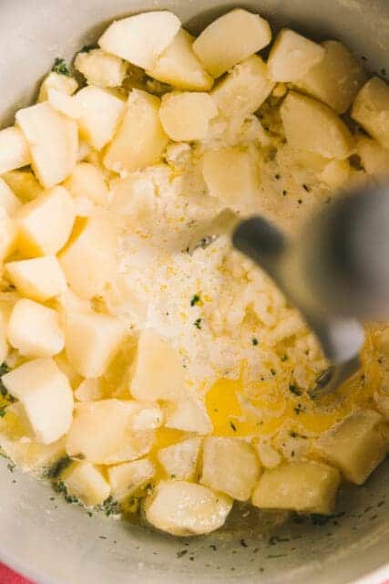 pouring warm milk into diced potatoes in a pot