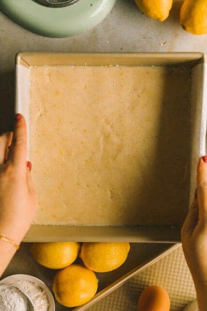 lining an 8x8 baking pan with parchment paper for lemon bar recipe