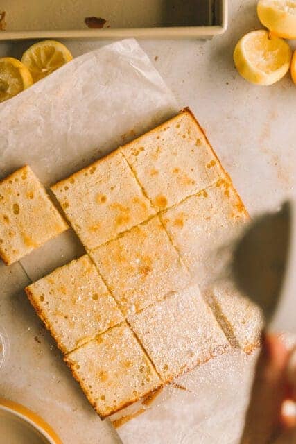 dusting powdered sugar on top of finished lemon bar recipe