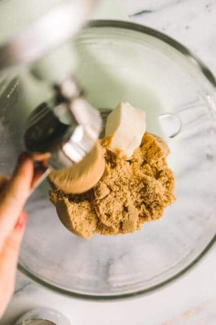 adding packed brown sugar into butter for white chocolate macadamia nut cookies recipe