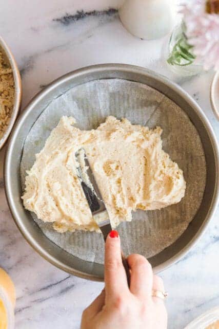 spreading lemon cake batter in a cake pan lined with parchment