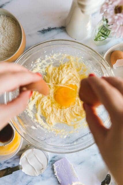 adding a large egg into bowl for lemon cake batter