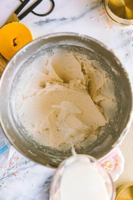 pouring in milk to mix ingredients for birthday cake recipes