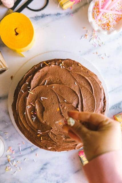 adding sprinkles onto a finished vintage birthday cake
