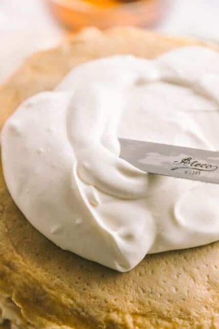 spreading soft whipped cream on top of crêpes with an offset spatula