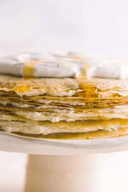 close up view of layers of crêpes with whipped cream on top