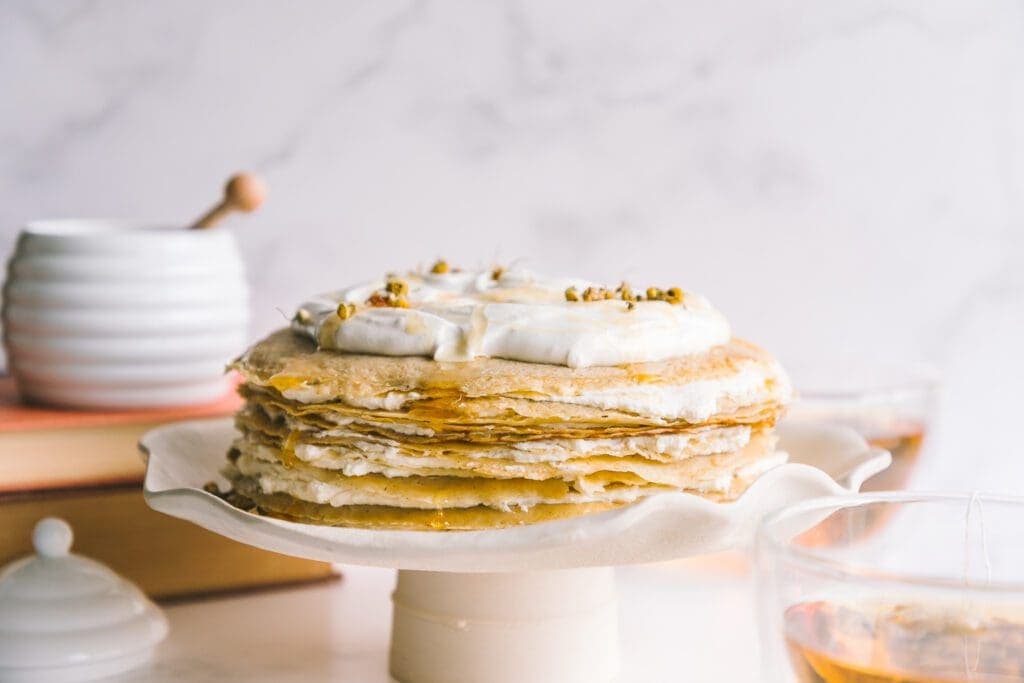honey chamomile crêpe cake on a white cake stand