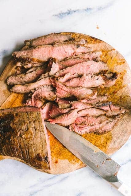 cutting flank steak to put onto the French dip sandwich