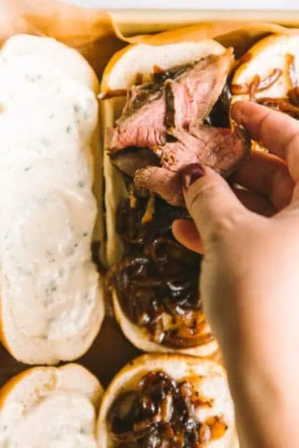 piling flank steak on a hoagie roll