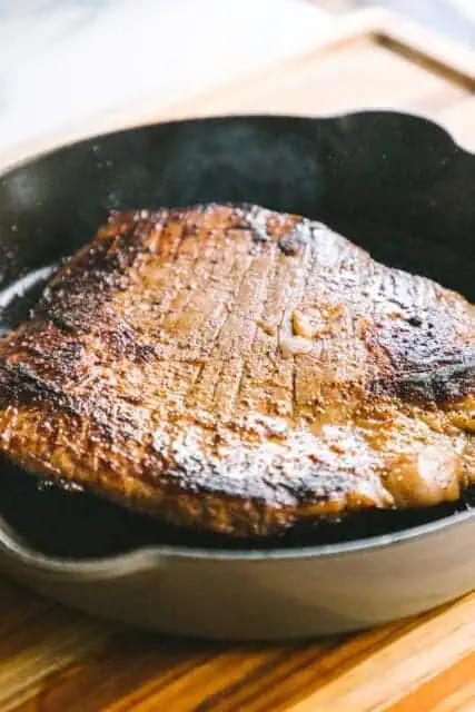 slightly charred flank steak cooked in a cast iron to make a French dip sandwich