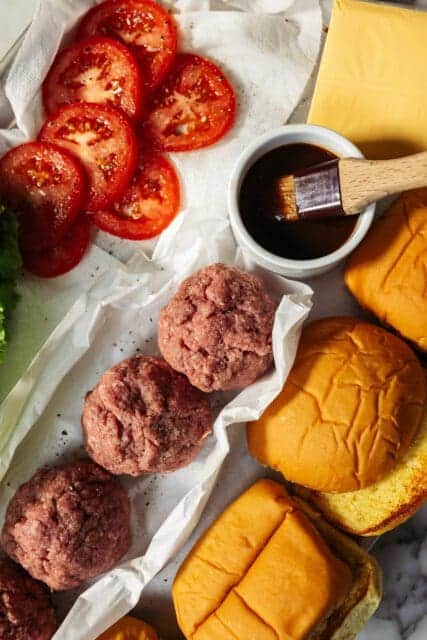 close up of root beer marinade, ground beef, and tomatoes for smash burger recipe