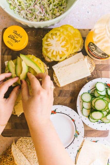 adding avocado to the tomatoes on the sandwich