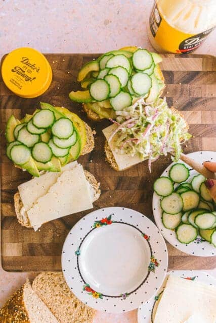 adding cucumbers and slaw to the tomato sandwich