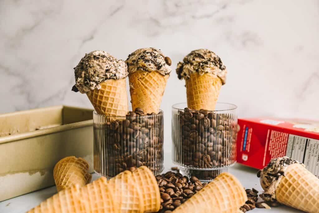 coffee ice cream in cones propped up in a cup of coffee beans