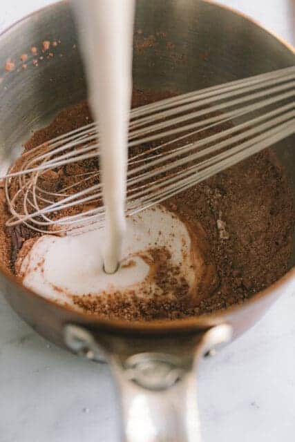 adding coconut milk to warm chocolate