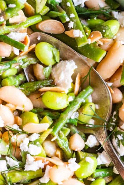 spoonful of spring salad with edamame, asparagus, cannellini beans, slivered almonds, and crumbled cheese