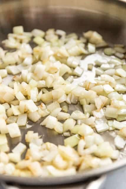 onions sizzling in a pan, softening and becoming translucent