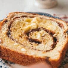 spreading butter all over a slice of cinnamon raisin swirl bread