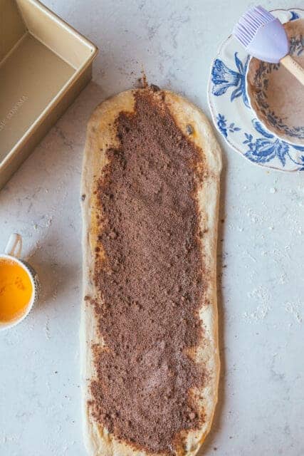 raisin bread dough topped with cinnamon ready to roll