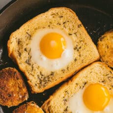 two slices of egg in a hole with texas toast in a cast iron skillet